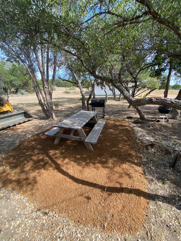 Rustic picnic table and grills under trees